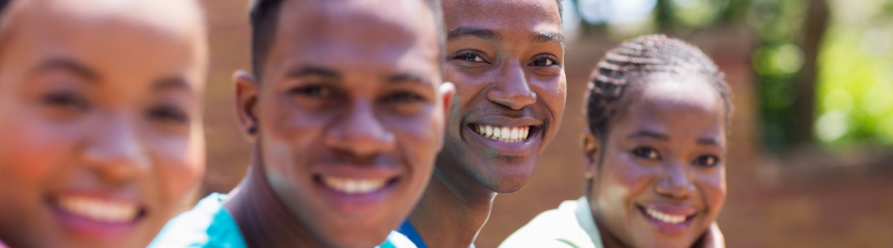 A group of young adults smiling in front of a brick wall.